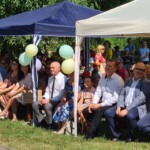 Uczestnicy i zaproszeni goście siedzący na ławkach przed sceną