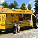 Dzieci stojące przy food trucku z kurczakiem i frytkami.