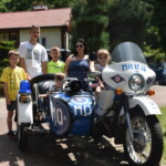 Dzieci z rodziny zastępczej stojące przy motocyklu policyjnym